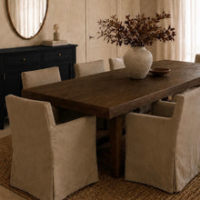 Load image into Gallery viewer, Dining room with a walnut table and beige chairs, featuring a vase with branches on the table, neutral rug and brass lighting