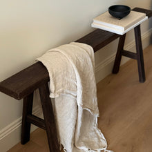 Load image into Gallery viewer, Wooden bench with a beige towel draped over it, against a neutral wall.