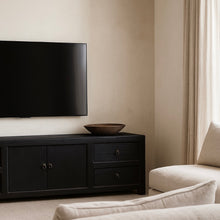 Load image into Gallery viewer, Living room with a black TV stand, television, and beige sofa.
