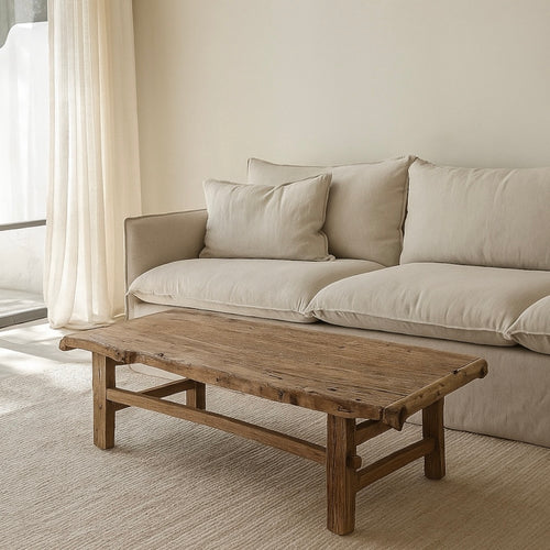 Beige sofa with cushions and a wooden coffee table in a living room setting.