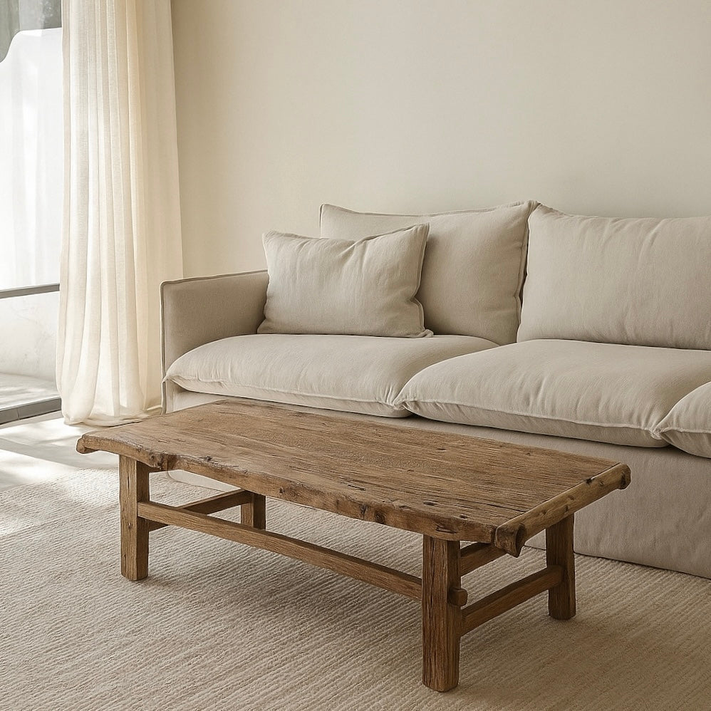 Beige sofa with cushions and a wooden coffee table in a living room setting.